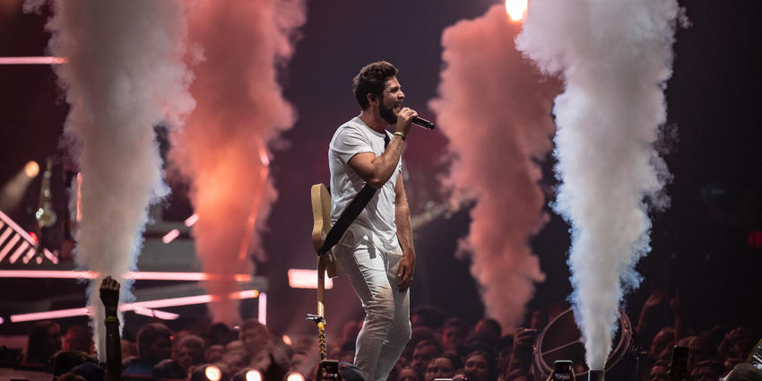 Thomas Rhett performs on stage with theatrical smoke columns in background