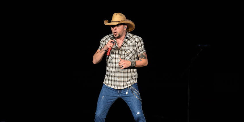 Jason Aldean, wearing signature cowboy hat, rolled up sleeved flannel shirt & jeans, sings to the BJC crowd. 