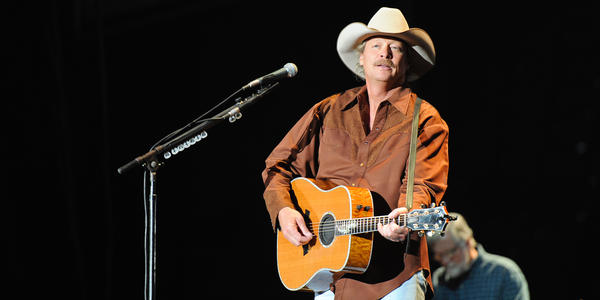 Alan Jackson wearing a cowboy hat, plays guitar on stage at the Bryce Jordan Center. 