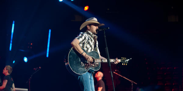 Jason Aldean sings into standing microphone & plays guitar for the sold out audience at the Bryce Jordan Center in 2010.