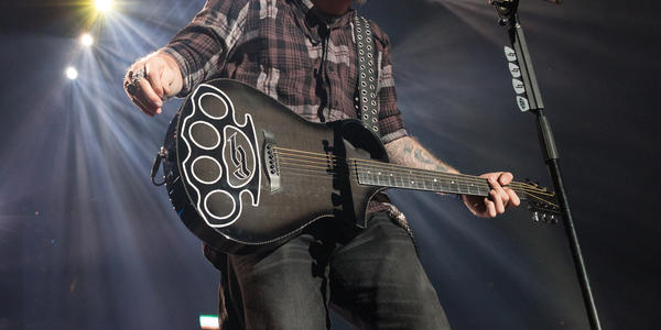 Brantley Gilbert sings into microphone on stage while holding guitar during concert at BJC.