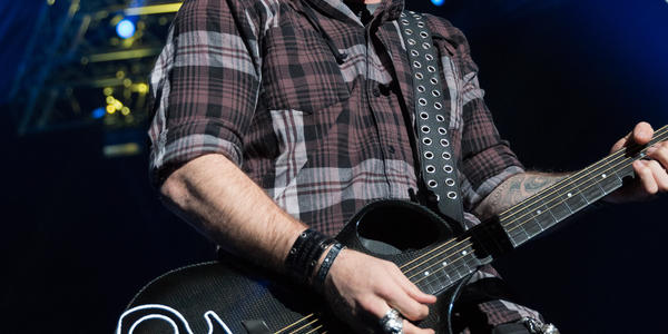 Brantley Gilbert plays guitar and sings into standing microphone during concert at BJC in 2017.