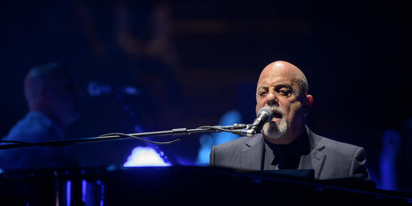 Billy Joel sings and plays his piano on stage for the audience at the Bryce Jordan Center.