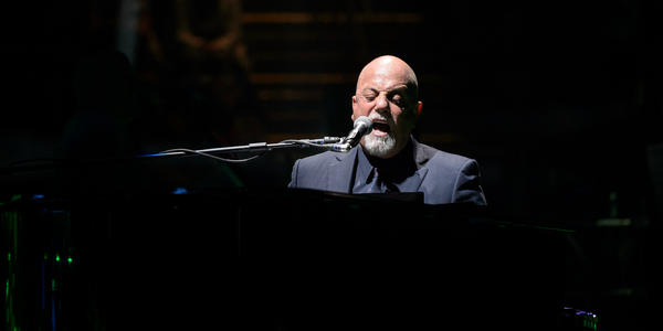 Billy Joel sings and plays his piano on stage for the audience at the Bryce Jordan Center.
