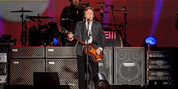 Paul McCartney, plays guitar and sings into standing microphone for the sold out BJC crowd.