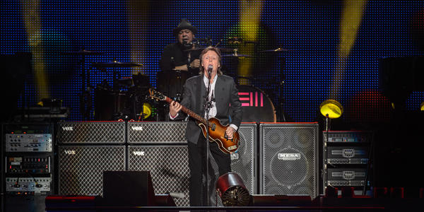 Paul McCartney, plays guitar and sings into standing microphone for the sold out BJC crowd