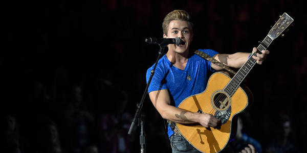 Hunter Hayes sings into a standing microphone while playing his guitar for the audience at the BJC.