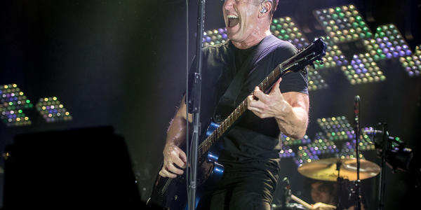 Nine Inch Nails lead singer screams into the microphone while playing guitar on stage at the Bryce Jordan Center in 2013.