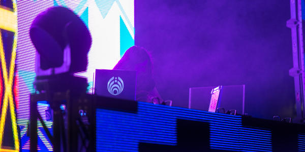 DJ Bassnector mixes in front of a brightly rainbow colored screen at the BJC in 2013.