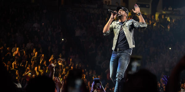 Luke Bryan sings into handheld microphone to a packed crowd during his concert at the BJC.