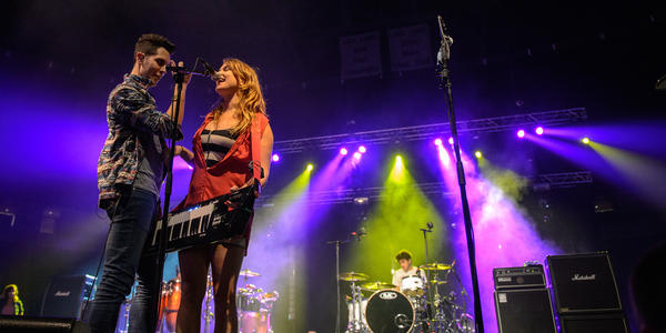 Female vocalist shares microphone with lead singer of Cobra Starship while playing keytar at the BJC in 2012.