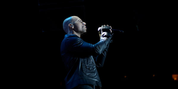 Lead singer, Chris Daughtry, holds microphone and sings to the crowd.