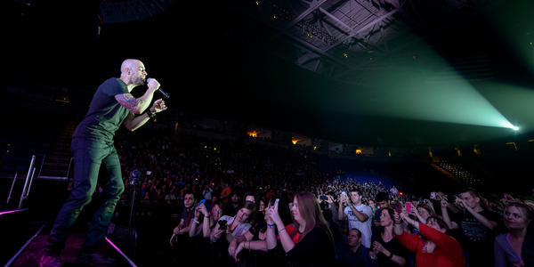 Stage left view of Chris Daughtry on stage singing with the audience gathered around the stage at the BJC.