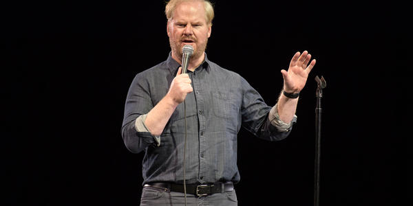 Jim Gaffigan speaking into microphone to the crowd at the BJC.
