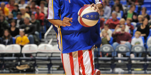 Globetrotter wearing their signature red, white & blue uniform dribbles down the BJC basketball court.