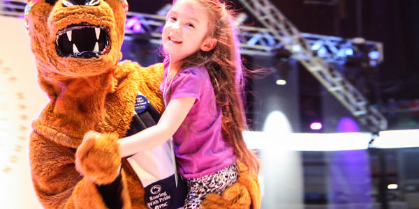 Nittany Lion dances on stage with a THON child during THON 2014.
