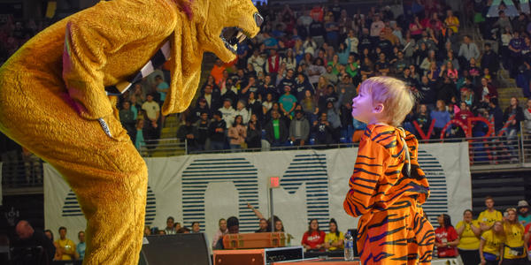 Thon child dressed in tiger costume looks up at PSU Nittany Lion