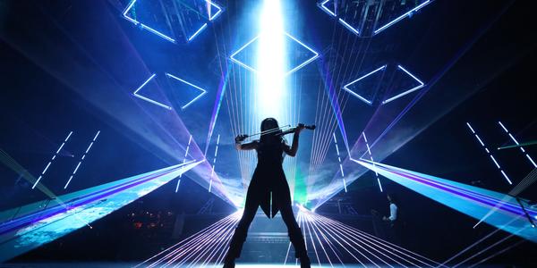 Silhouette of Trans-Siberian Orchestra's violinist performing in front of a mix of blue laser lights at the BJC in 2013.